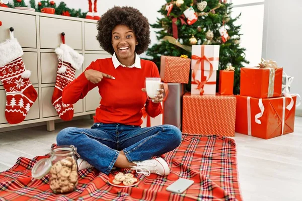 若いですアフリカ系アメリカ人女性とともにアフロ髪食べるペストリーによって座ってクリスマスツリー指して指へ一人の自己笑顔幸せと誇り — ストック写真