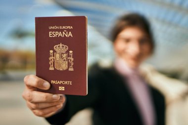 Genç ve güzel iş kadını gülümseyerek şehirde İspanya pasaportu taşıyor..
