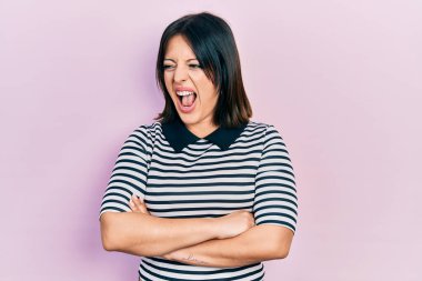 Kollarını kavuşturmuş genç İspanyol bir kadın kızgın ve kızgın çığlıklar atıyor öfkeyle bağırıyor. öfke ve agresif konsept. 