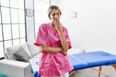 Evde fizyoterapist olarak çalışan genç sarışın kadın ağzını eliyle kapatmaktan sıkılmış. Huzursuz ve uykulu.. 