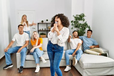 Bir grup genç arkadaş evde mikrofon kullanarak şarkı söylüyor..