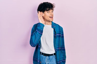 Yakışıklı hippi genç adam, günlük beyaz tişört ve klasik tişört giyiyor. Kulaktan kulağa gülümsüyor. Dedikoduları ve dedikoduları dinliyor. Sağırlık kavramı. 