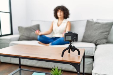 Orta Doğulu genç bir kadın evde yoga dersi veriyor.