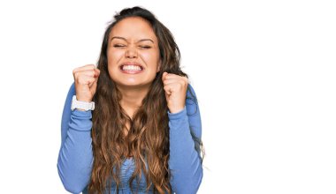 Gündelik kıyafetler giyen genç İspanyol kız başarı için heyecanlı kolları havada ve gözleri kapalı zaferi kutlarken gülümsüyor. Kazanan konsept. 