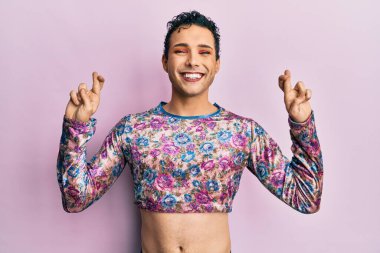 Makyaj elbisesi giyen yakışıklı adam umut ve gözlerin kapalı gülümseyerek el işareti yapıyor. Şans ve batıl inançlar. 