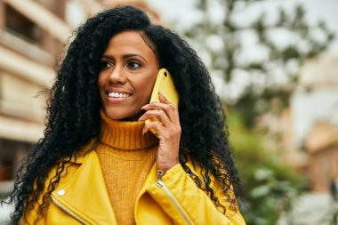 Orta yaşlı Afro-Amerikan kadın şehirde akıllı telefondan konuşuyor..