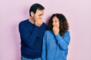 Orta yaşlı bir çift İspanyol kadın ve erkek birbirine sarılıyor ve birlikte duruyorlar. Gergin ve gergin görünüyorlar. Elleri ağızlarında ve tırnaklarını yiyorlar. anksiyete. 