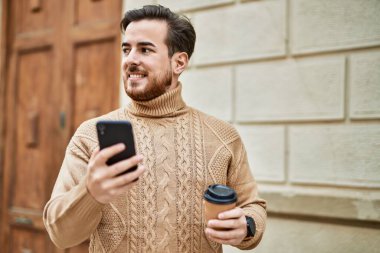 Kafkasyalı genç adam akıllı telefon kullanıyor. Şehirde kahve içiyor..