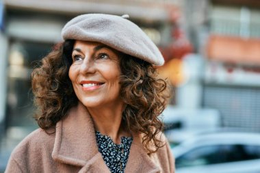 Orta yaşlı İspanyol kadın gülümseyerek şehirde mutlu mesut dikiliyor..