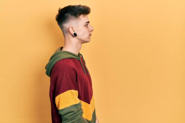 Kulakları genişlemiş, sıradan bir kazak giyen rahat bir profil pozu veren, kendine güvenen bir gülümsemesi olan beyaz bir çocuk.. 