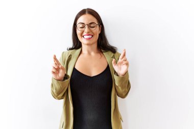 Genç esmer kadın izole edilmiş arka planda duruyor. Umut ve gözler kapalı gülümseyerek el işareti yapıyor. Şans ve batıl inançlar. 