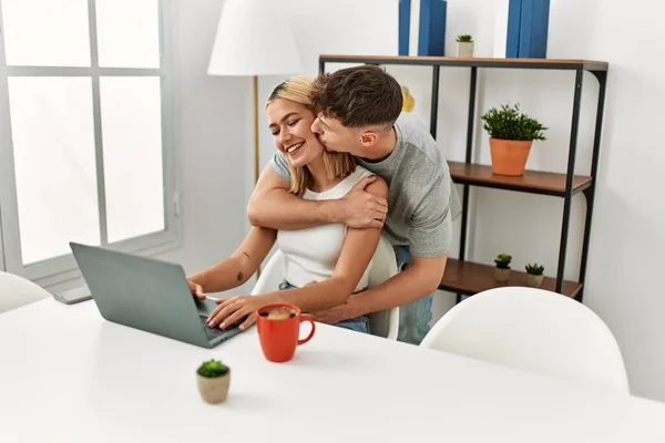 Young Caucasian Couple Hugging Kissing Using Laptop Sitting Desk Home — Stock Photo, Image
