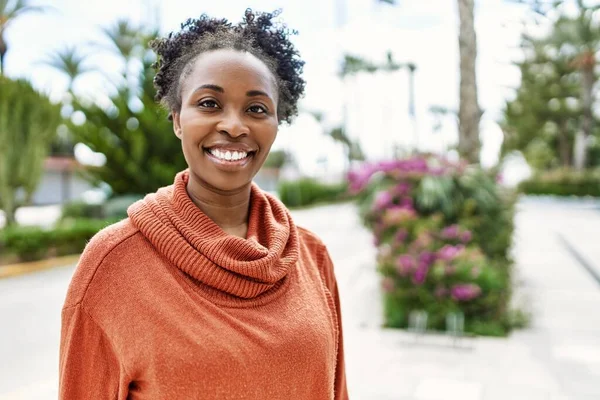 Genç Afrikalı Amerikalı kız gülümseyerek şehirde mutlu mesut duruyor..