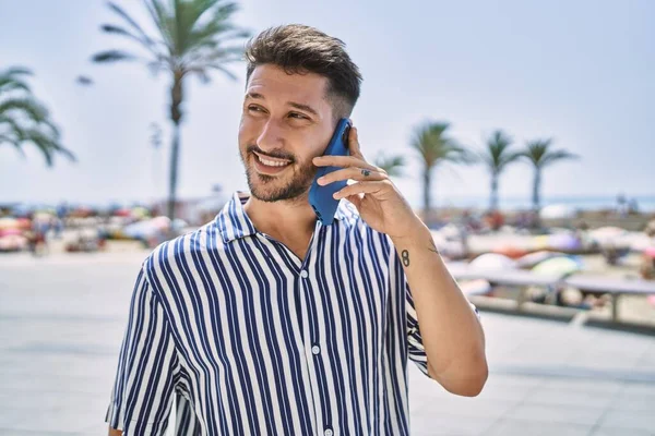 Genç yakışıklı adam deniz kenarında telefonla konuşuyor.