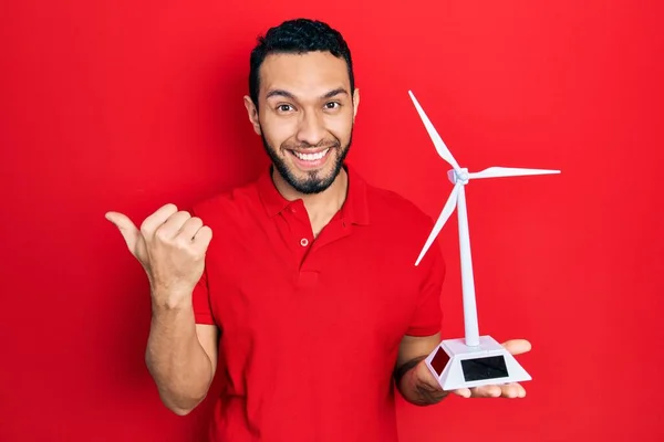再生可能エネルギーのための太陽の風車を保持髭を持つヒスパニック系の男親指を持ちます側まで笑顔幸せなオープン口で — ストック写真