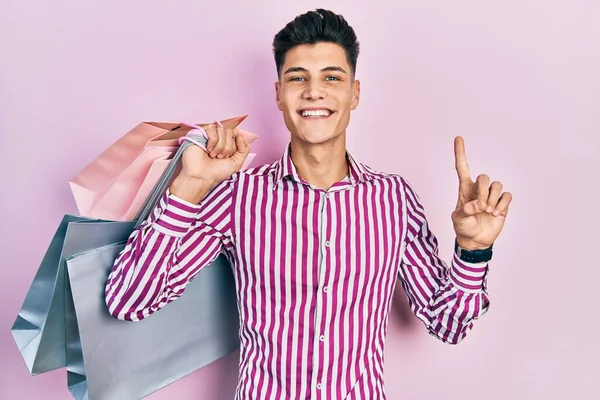 Joven Hispano Sosteniendo Bolsas Compras Sonriendo Con Una Idea Pregunta —  Fotos de Stock