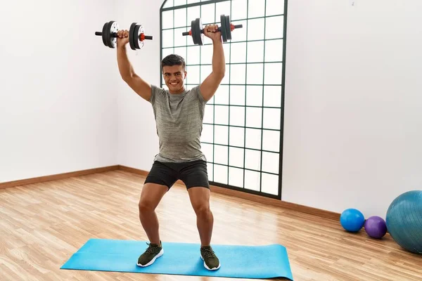 Giovane Uomo Ispanico Sorridente Allenamento Fiducioso Utilizzando Manubri Centro Sportivo — Foto Stock