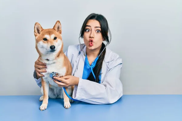 美しいパニック獣医師女性チェック犬の健康作る魚の顔で口と目を細めて クレイジーでコミカルな — ストック写真