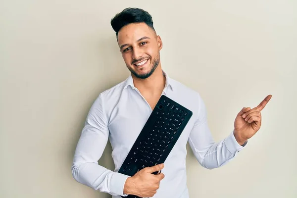 Genç Arap Adam Elinde Bilgisayar Klavyesi Tutarken Gülümsüyor — Stok fotoğraf