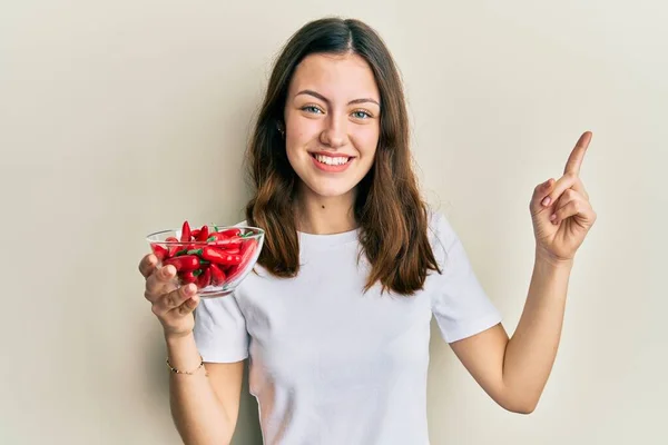 Mladá Bruneta Žena Drží Červené Papriky Úsměvem Šťastný Ukazující Rukou — Stock fotografie