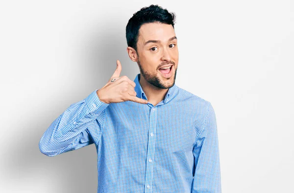 Sakallı, sıradan iş gömleği giyen, gülümseyen, el ve parmaklarıyla telefonla konuşan İspanyol bir adam. iletişim kavramları. 