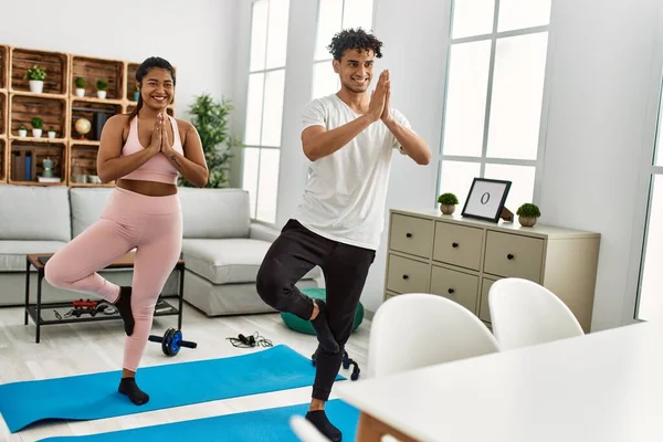 Gülümseyen genç Latin çift evde mutlu yoga pozu veriyor..
