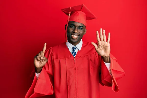 自信と幸せ笑顔ながら若いアフリカ系アメリカ人男性卒業キャップと式のローブを着て指の数6を示すと指摘します — ストック写真