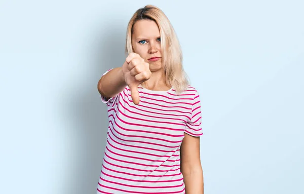 カジュアルな服を着ている若い白人女性は 親指を下にジェスチャーで拒絶と否定を示す不満と怒りを見ています 悪い表現 — ストック写真
