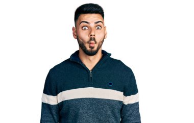 Sakallı, kışlık süveter giyen dudakları balıklı surat yapan, çılgın ve komik bir jest yapan genç bir İspanyol. Komik ifade. 