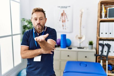 Orta yaşlı fizyoterapist. Ağrı kesici kliniğinde çalışıyor. Kameraya bakıyor. aşk ifadesi. 