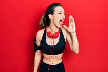 Spor kıyafetleri giyen, kulaklık takan, el pençe divan duran Latin kökenli genç bir kız. iletişim konsepti. 