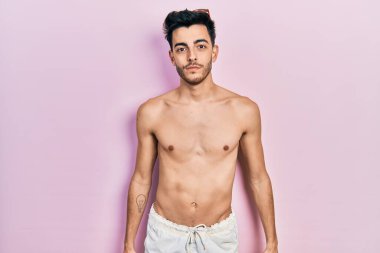 Yüzünde ciddi bir ifade olan, mayo giyen genç İspanyol bir adam. Basit ve doğal bir şekilde kameraya bakıyorsun.. 