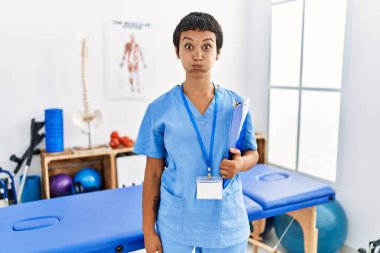 Kısa saçlı, İspanyol bir kadın ağrı kesici kliniğinde çalışıyor. Komik suratlı yanakları şişiriyor. Havayla şişmiş ağız, çılgın bir ifade.. 