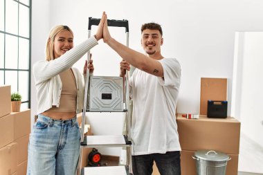 Kafkasyalı genç çift yeni evinde işçi merdivenlerini tutarken beşlik çakıyor..