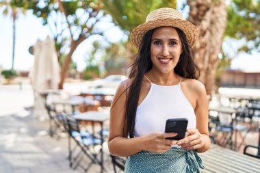 Sokakta akıllı telefon kullanan, kendine güvenen genç İspanyol kadın.