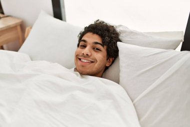 Genç İspanyol adam mutlu bir şekilde gülümsüyor. Yatak odasında yatıyordu..