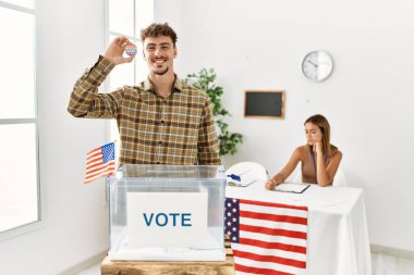 Seçmen kolejinde oy sandığının yanında rozeti olan genç Amerikalı seçmen..