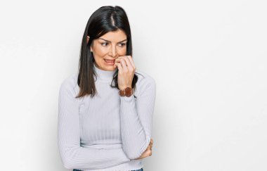 Güzel esmer kadın, gündelik kıyafetler giyiyor. Stresli ve gergin görünüyor. Elleri ağızdan tırnak yiyor. anksiyete. 