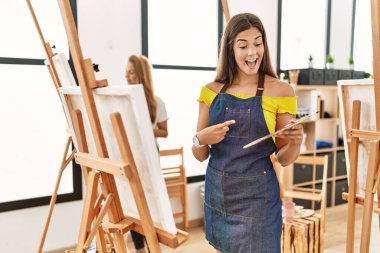 Sanat sınıfındaki genç İspanyol kadın gülümseyerek mutlu bir şekilde elini ve parmağını gösterdi. 