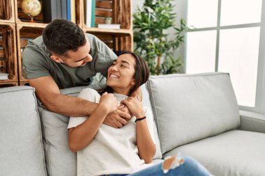 Kanepede oturan genç latin çift evde sarılıyorlar..