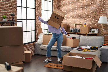 Genç Afrikalı Amerikalı kadın yeni evinde kafasında karton kutuyla dans ediyor.