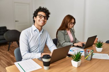 Ofiste dizüstü bilgisayarla çalışırken gülümseyen iki iş adamı..