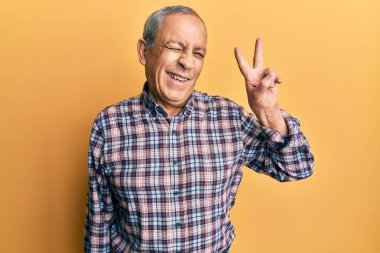 Gri saçlı, sıradan tişörtlü, mutlu yüzüyle kameraya göz kırpan yakışıklı, son sınıf öğrencisi zafer işareti yapıyor. İki numara.. 