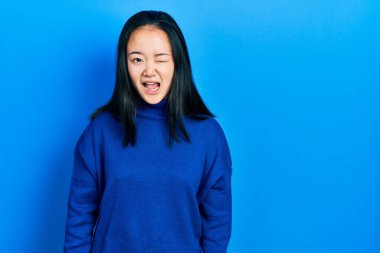 Gündelik giysiler giymiş genç Çinli kız kameraya seksi bir ifadeyle bakıyor, neşeli ve mutlu bir yüzle.. 