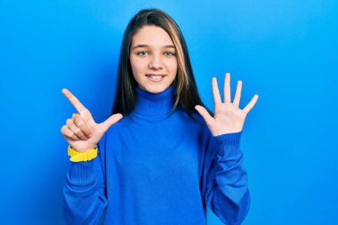 Balıkçı yaka kazak giyen genç esmer kız yedi numarayı gösterip işaret ederken kendinden emin ve mutlu bir şekilde gülümsüyor.. 