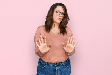 Sıradan kıyafetler giyen ve gözlüklü genç bir kadın. Avuçlarını hareket ettiriyor. Korkmuş ve iğrenç bir ifadeyle reddediyor. Dur ve yasakla. 