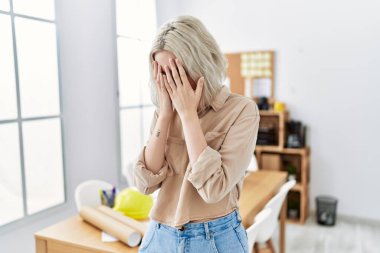 İnşaat ofisindeki genç, güzel, beyaz bir kadın. Ağlarken suratını ellerle kapatan üzgün bir ifade. depresyon kavramı. 