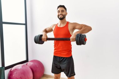 Genç Arap adam gülümsüyor spor merkezinde halterleri olan kendine güvenen bir antrenman.