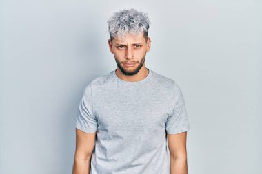 Modern boyalı saçlı, günlük gri tişörtlü, sıkıntılı ve endişeli, sinirli ve korkmuş bir İspanyol genç. hüzünlü ifade. 