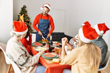 Mutlu bir şekilde gülümseyen bir grup genç adam evde servis etmek için kızarmış hindi kesiyor..